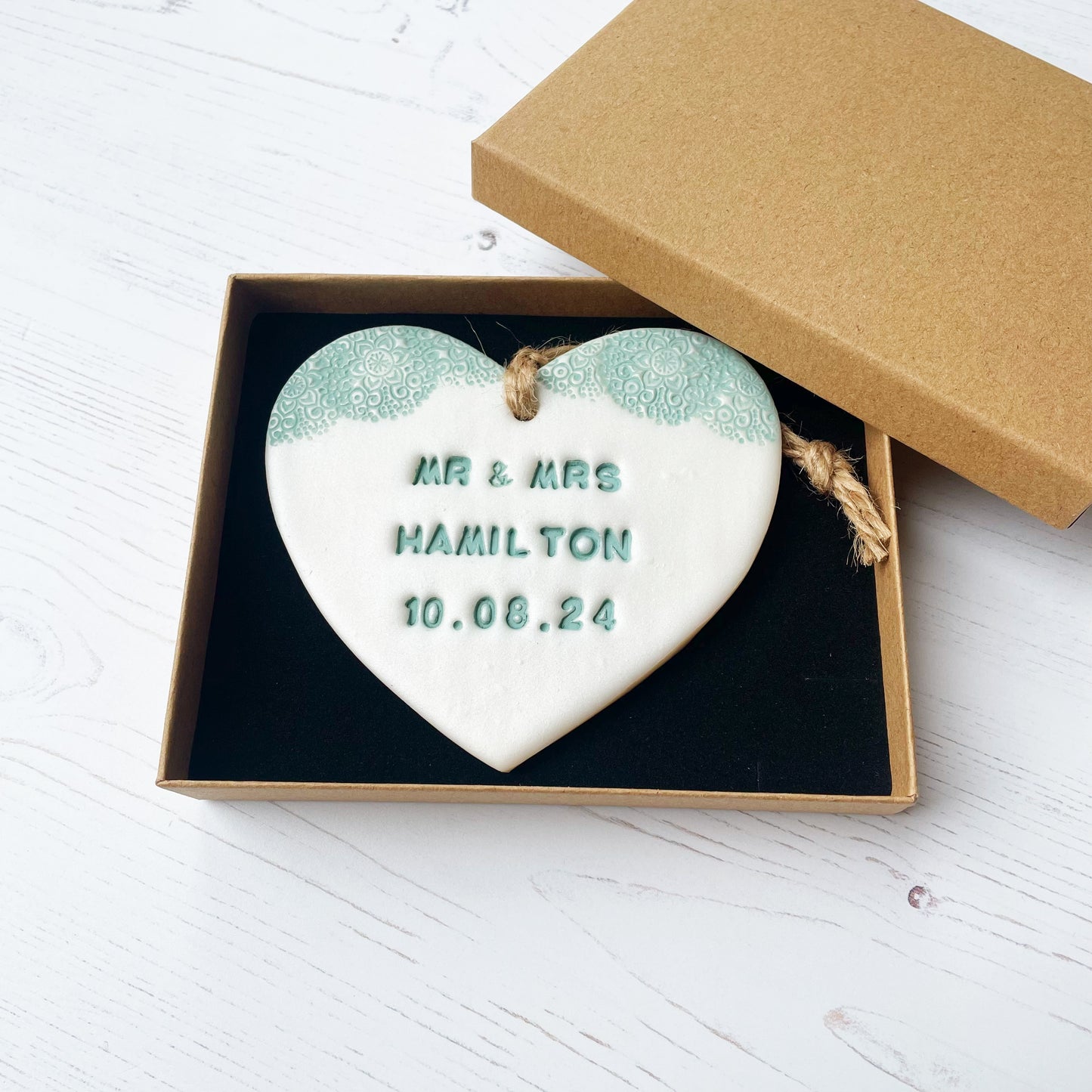 Personalised wedding gift, pearlised white clay hanging heart with a sage green lace edge at the top of the heart, the heart is personalised with MR & MRS HAMILTON 10.08.24