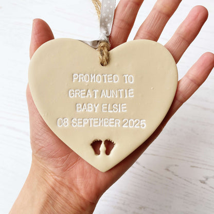 Beige clay hanging heart with baby feet cut out of the bottom and white personalisation, the heart is personalised with PROMOTED TO GREAT AUNTIE BABY ELSIE 08 SEPTEMBER 2025