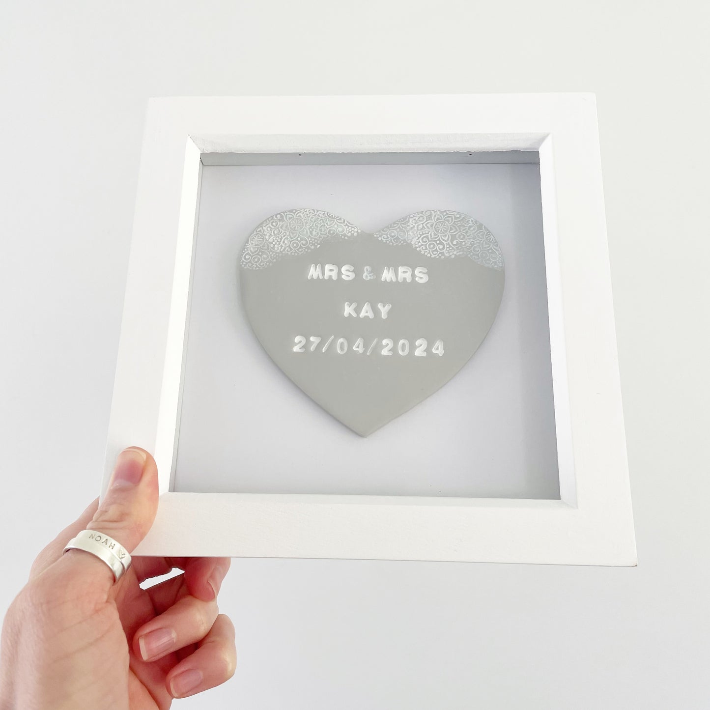 Personalised framed wedding gift, grey clay heart with a white lace edge at the top of the heart in a white box frame, the heart is personalised with MRS & MRS KAY 27/04/2024