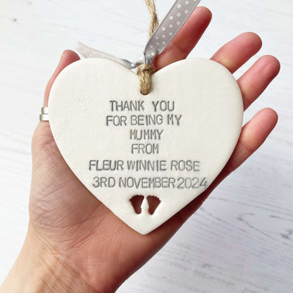 Personalised Mother’s Day gift, pearlised white clay hanging heart with baby feet cut out at the bottom of the heart, the heart is personalised with THANK YOU FOR BEING MY MUMMY FROM FLEUR WINNIE ROSE 3RD NOVEMBER 2024