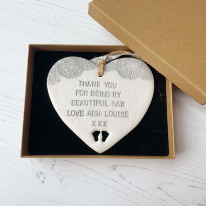 Personalised Mother’s Day gift, pearlised white clay hanging heart with baby feet cut out at the bottom of the heart and a grey lace edge at the top of the heart, the heart is personalised with THANK YOU FOR BEING MY BEAUTIFUL MAM LOVE ARIA LOUISE XXX
