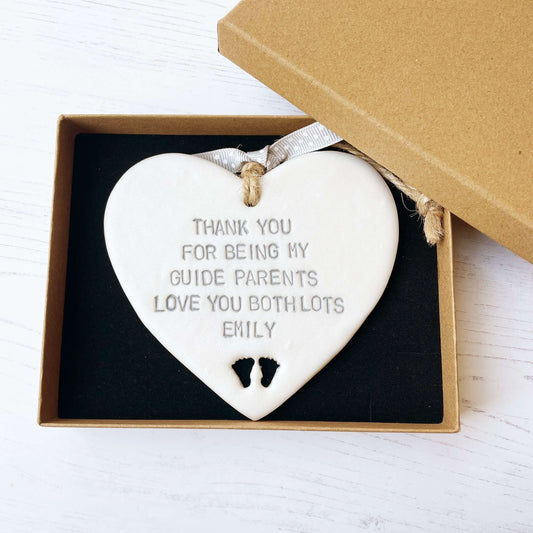 Personalised guide parents gift, pearlised white clay hanging heart with baby feet cut out of the bottom, the heart is personalised with THANK YOU FOR BEING MY GUIDE PARENTS LOVE YOU BITH LOTS EMILY