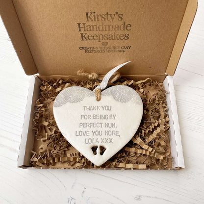 Personalised Mother’s Day gift, pearlised white clay hanging heart with baby feet cut out at the bottom of the heart and a grey lace edge at the top of the heart, the heart is personalised with THANK YOU FOR BEING MY PERFECT MUM. LOVE YOU MORE, LOLA XXX