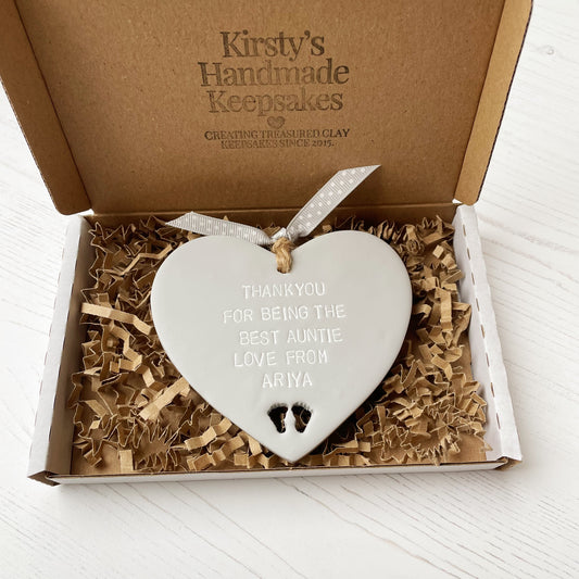 Grey clay hanging heart with baby feet cut out of the bottom and white personalisation, the heart is personalised with THANKYOU FOR BEING THE BEST AUNTIE LOVE FROM ARIYA